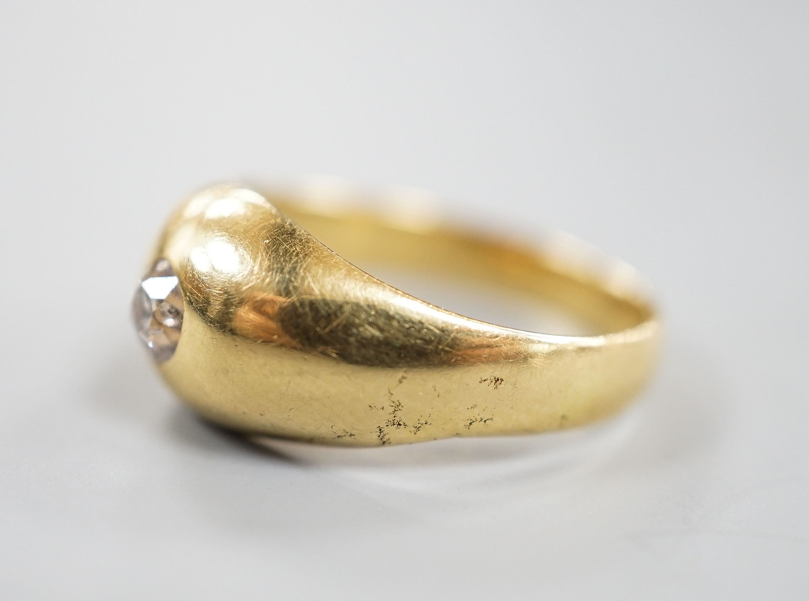 A yellow metal (stamped 18) and gypsy set solitaire diamond ring, size R, gross 5.6 grams.